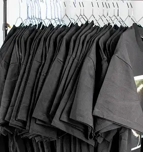 පොඩි clothing studio එකක එල්ලලා තියෙන කළු t-shirts රාක්කයක්